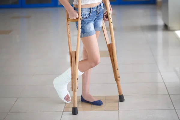 Молодая девушка на костылях в коридоре больницы — стоковое фото