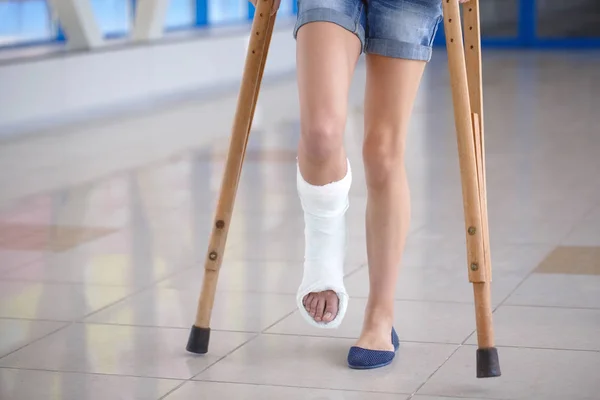 Uma jovem está de muletas no corredor do hospital. — Fotografia de Stock