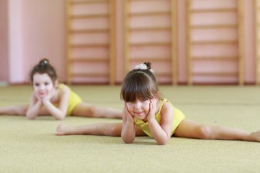 Genç kızlar spor salonunda jimnastik yapıyor.