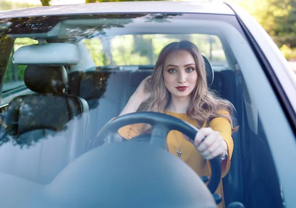 Una joven hermosa chica está conduciendo un coche . — Foto de Stock