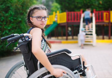 Kırık bir bacak bir kızla Bahçesi önünde tekerlekli sandalyede oturur.