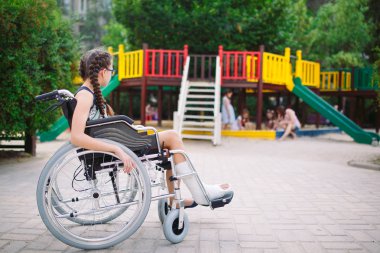Kırık bir bacak bir kızla Bahçesi önünde tekerlekli sandalyede oturur.