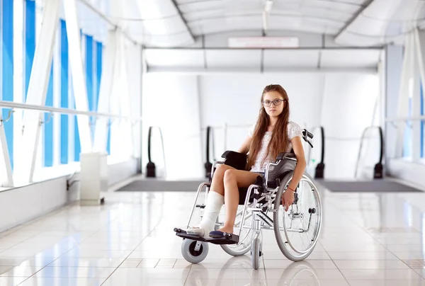 Uma jovem em uma cadeira de rodas está no corredor do hospital . — Fotografia de Stock