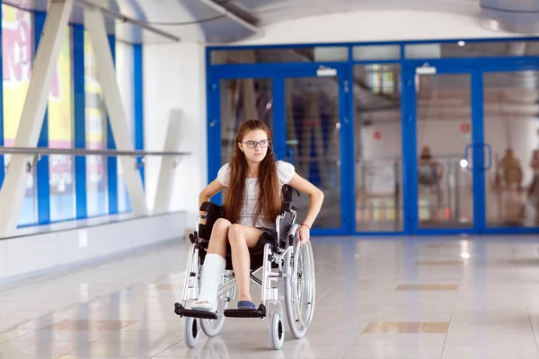 Tekerlekli sandalyede bir genç kız hastane koridorunda duran.