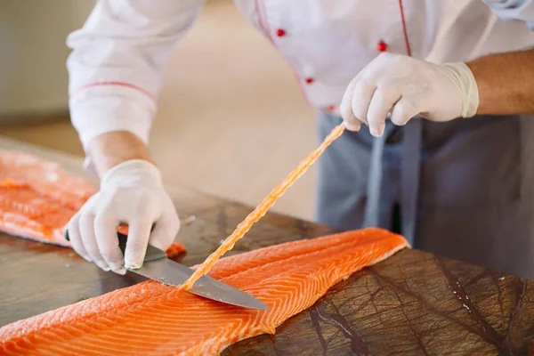 Lo chef taglia il salmone sul tavolo . — Foto Stock