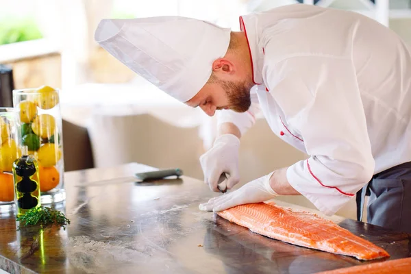 The chef cuts the salmon on the table.