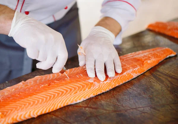 The chef cuts the salmon on the table. — Stock Photo, Image