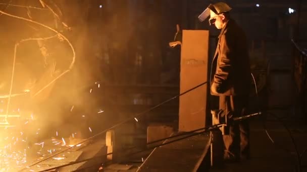 Завод по производству стали. Электрическая плавильная печь. Работник завода берет образец для металла — стоковое видео