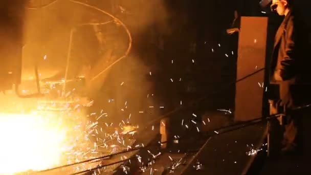 강철 생산을 위한 식물. 전기가 녹는 용광로. 공장에서 일하는 사람이 금속 샘플을 채취 한다 — 비디오
