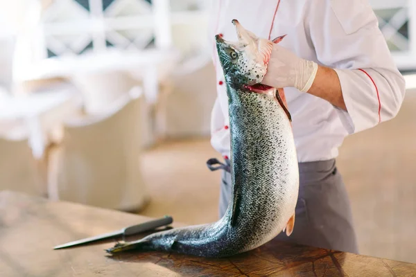 Chef keep the salmon. The chef cuts the salmon on the table. — Stock Photo, Image