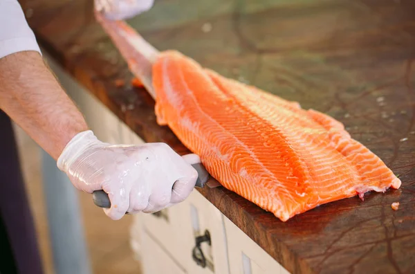 The chef cuts the salmon on the table. — Stock Photo, Image