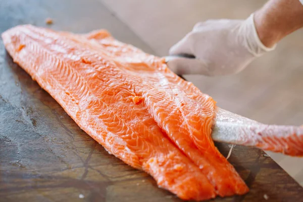 The chef cuts the salmon on the table. — Stock Photo, Image