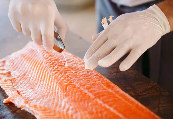 Шеф-кухар вирізає лосось на столі . — стокове фото