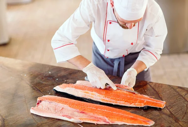 O chef corta o salmão na mesa — Fotografia de Stock