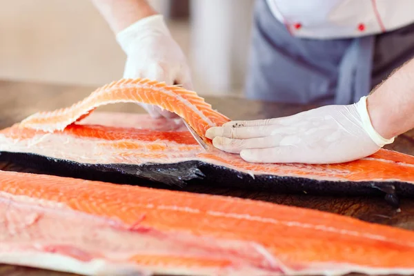 The chef cuts the salmon on the table — Stock Photo, Image