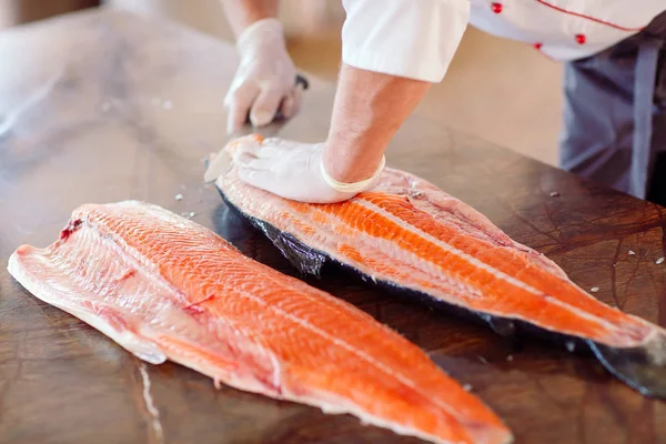 O chef corta o salmão na mesa — Fotografia de Stock