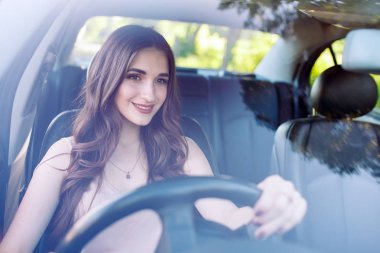 Genç güzel bir kız araba kullanıyor.