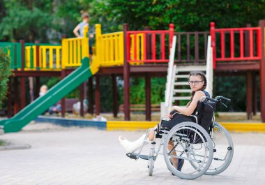 Kırık bir bacak bir kızla Bahçesi önünde tekerlekli sandalyede oturur