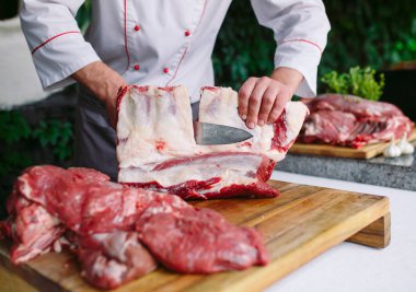 Aşçı bir adam lokantada bıçakla et keser.