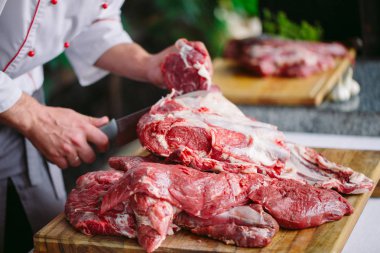 Aşçı bir adam lokantada bıçakla et keser.