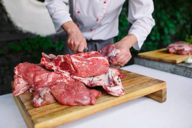 Aşçı bir adam lokantada bıçakla et keser.