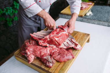 Aşçı bir adam lokantada bıçakla et keser.