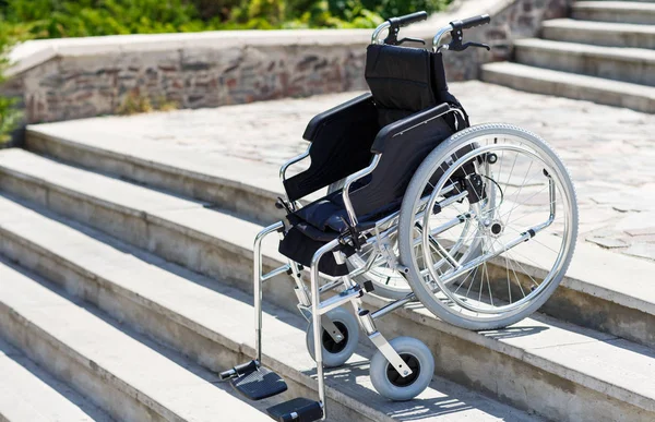 Cadeira de rodas perto dos degraus em um parque primaveril . — Fotografia de Stock