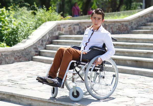 Młody mężczyzna na wózku inwalidzkim, który nie może zejć po schodach. — Zdjęcie stockowe