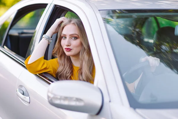 Una chica guapa joven está conduciendo un coche . — Foto de Stock