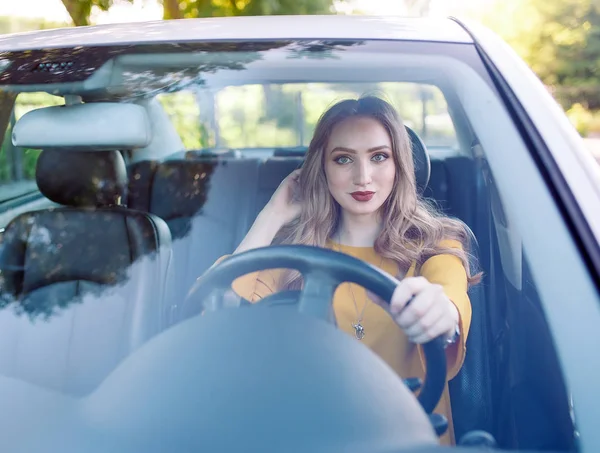 Una chica guapa joven está conduciendo un coche . — Foto de Stock