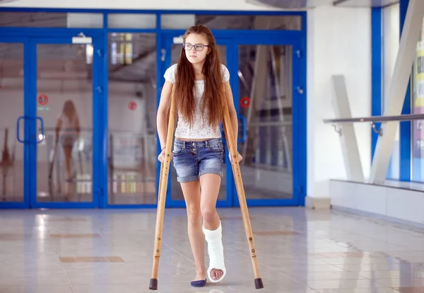 Uma jovem está de muletas no corredor do hospital. . — Fotografia de Stock