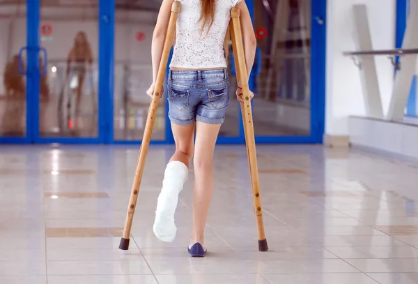 Uma jovem está de muletas no corredor do hospital. . — Fotografia de Stock