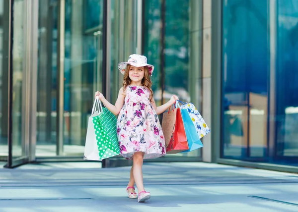 Το χαριτωμένο μικρό κορίτσι για ψώνια. Πορτρέτο του ένα παιδί με τσάντες αγορών. Για ψώνια. Κορίτσι. — Φωτογραφία Αρχείου