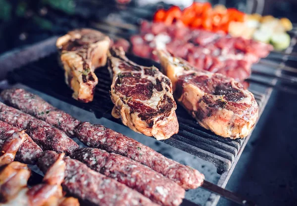 Large pieces of pickled meat on a grid in a restaurant. Mixed grilled meats