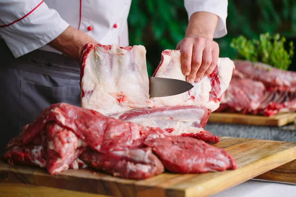 Aşçı bir adam lokantada bıçakla et keser.