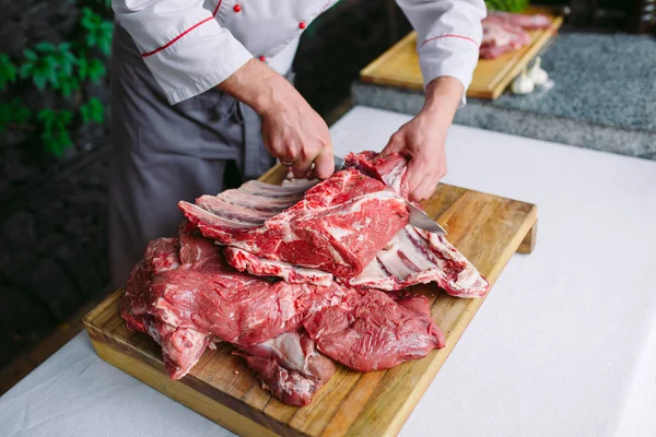 Aşçı bir adam lokantada bıçakla et keser.