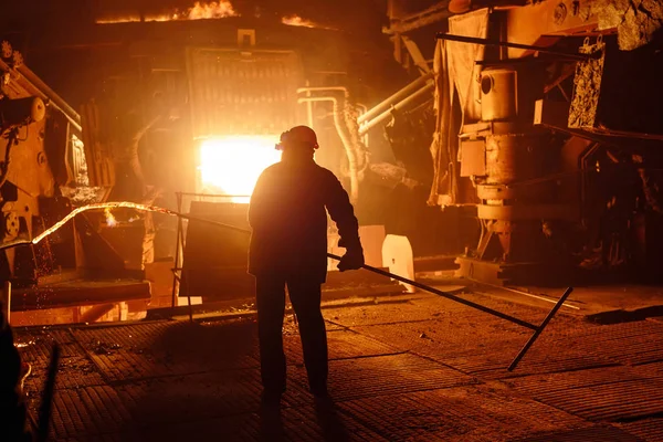 강철 생산을 위한 식물. 전기가 녹는 용광로. 공장에서 일하는 사람이 금속 샘플을 채취 한다 — 스톡 사진