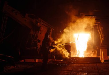 Çelik üretimi için bitki. Elektrikli bir eritme fırını. Fabrika işçisi metal için örnek alıyor.