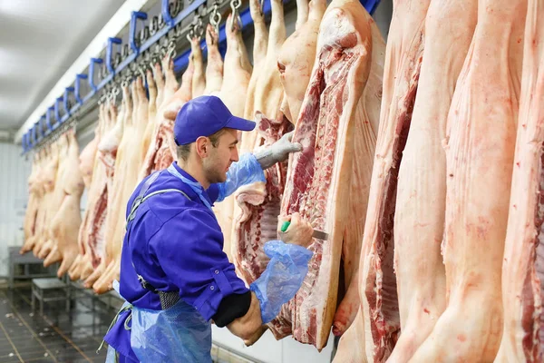 Carnicero cortando carne de cerdo en la fabricación de carne . — Foto de Stock