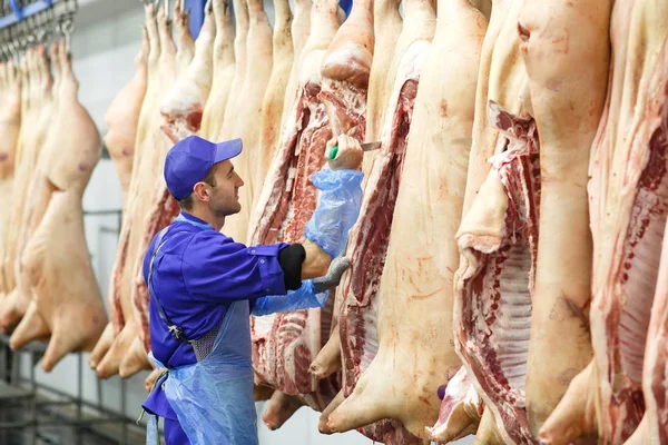 Carnicero cortando carne de cerdo en la fabricación de carne . — Foto de Stock