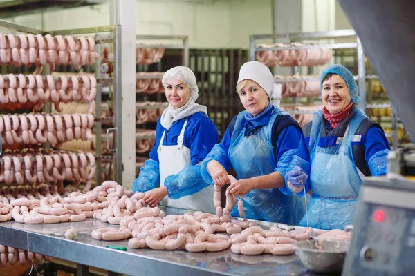 Macellai che lavorano salsicce in una fabbrica di carne . — Foto Stock