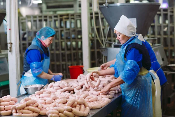 Macellai che lavorano salsicce in una fabbrica di carne . — Foto Stock