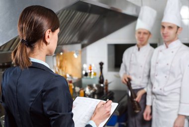 Restoran müdürü, mutfak personeline ticari mutfakta brifing veriyor..