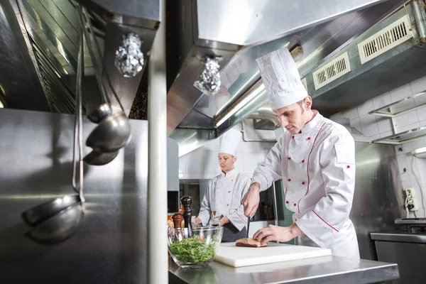 Kock styckning kött på hackbräda, professionell kock innehav kniv och styckning kött i restaurang. — Stockfoto
