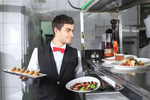 Il cameriere con i piatti pronti nella cucina del ristorante . — Foto Stock