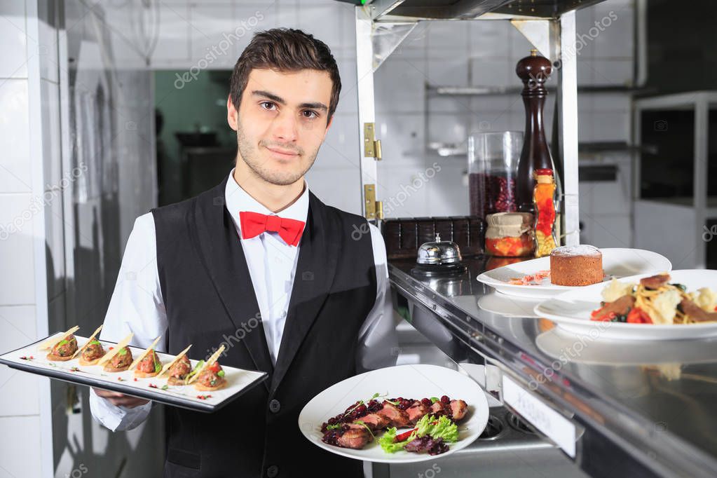 The waiter with the ready prepared dishes in the restaurant kitchen