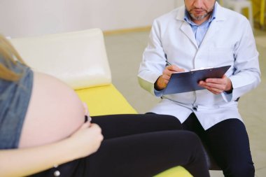 Jinekolog hamile kadına yankı fotoğrafı gösteriyor.