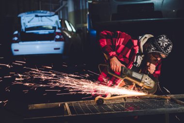 Servis istasyonu çalışanı elinde kıvılcım bir kaynak makinesi ile vücut onarım üretir