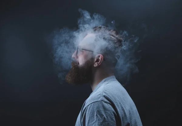Concept. Smoke enveloped the head man. Portrait of a Bearded, stylish man with smoke. Secondhand smoke. — Stock Photo, Image