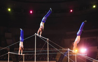 Acrobats perform exercises on the bar in the Circus arena. clipart